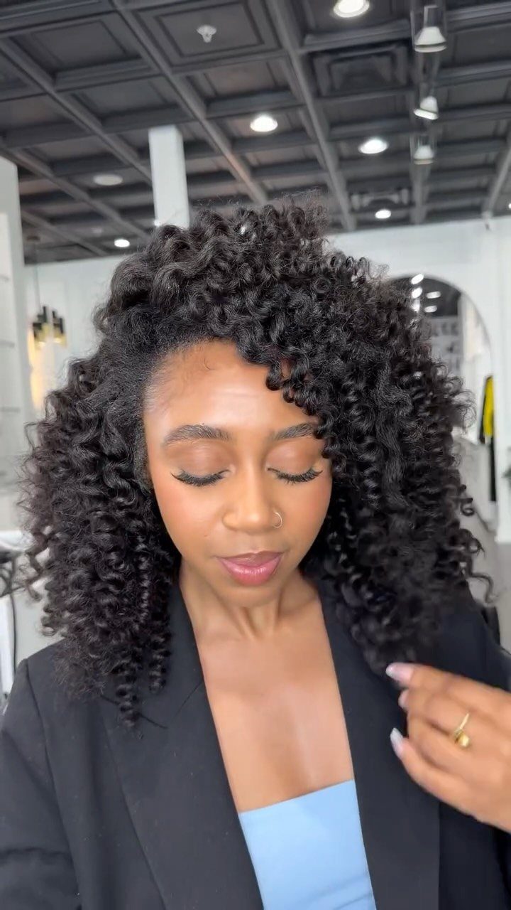 Woman with voluminous curly black hair styled in defined coils wearing a black blazer.