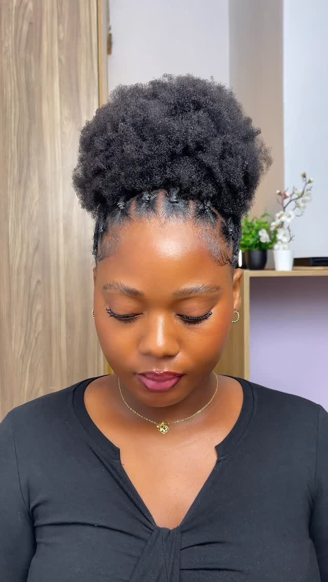 Woman with a voluminous high puff hairstyle and small twists at the base.