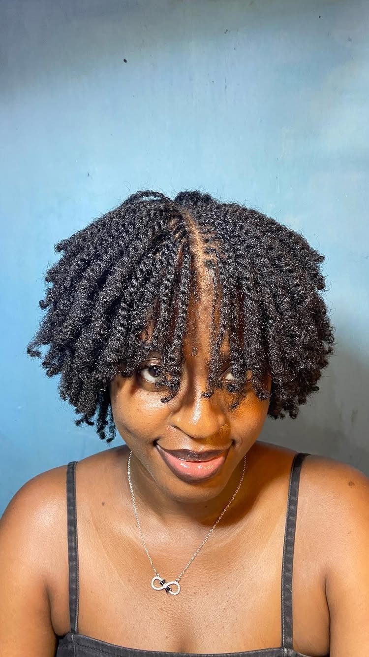 Woman with black hair styled in small, defined mini twists and a silver necklace.