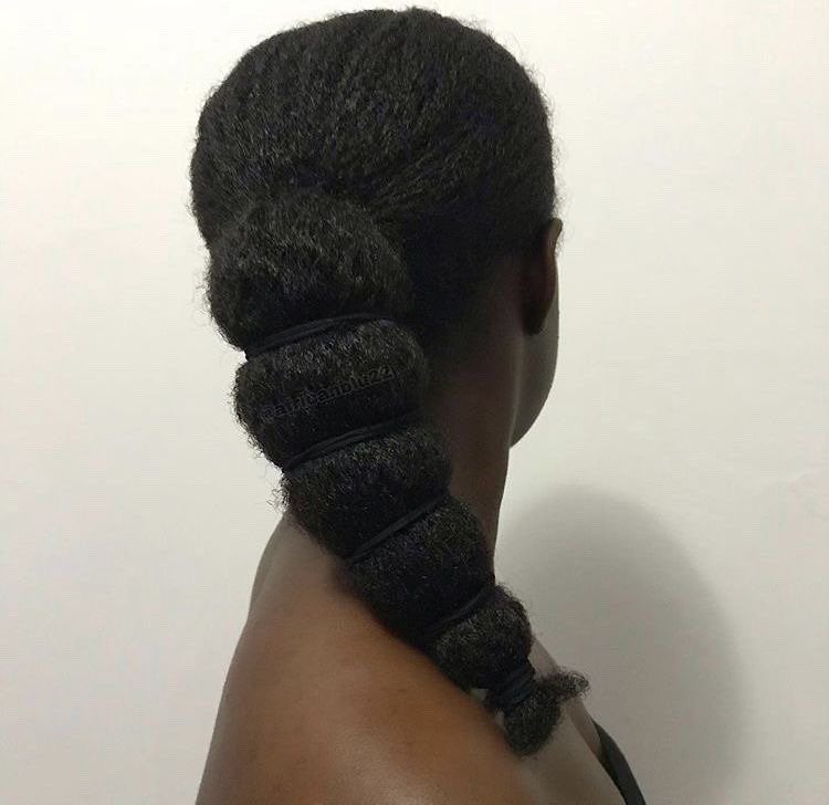 Textured 4c hair in a ponytail secured with multiple small black elastic bands.