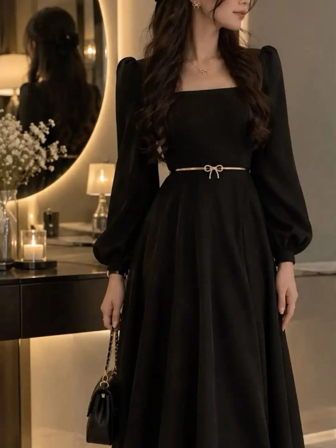 Woman in a black maxi dress with a thin gold bow belt