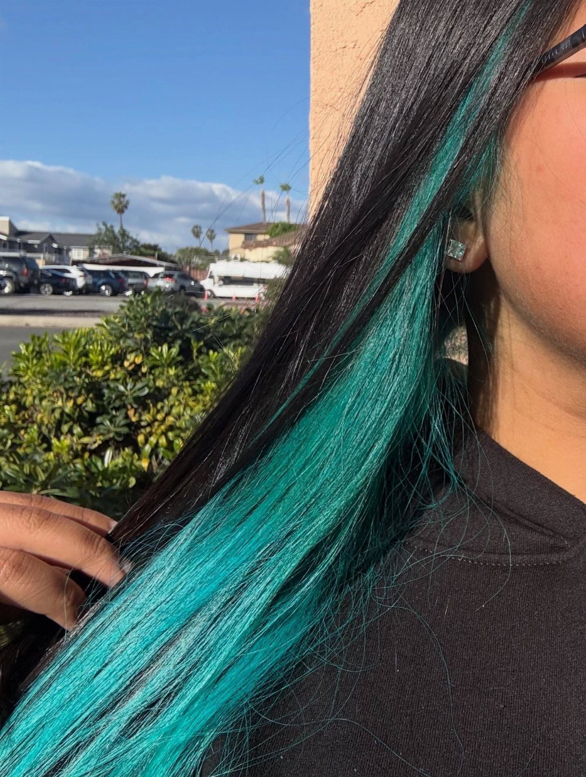 Long black hair with a thick, vibrant turquoise streak on the side.