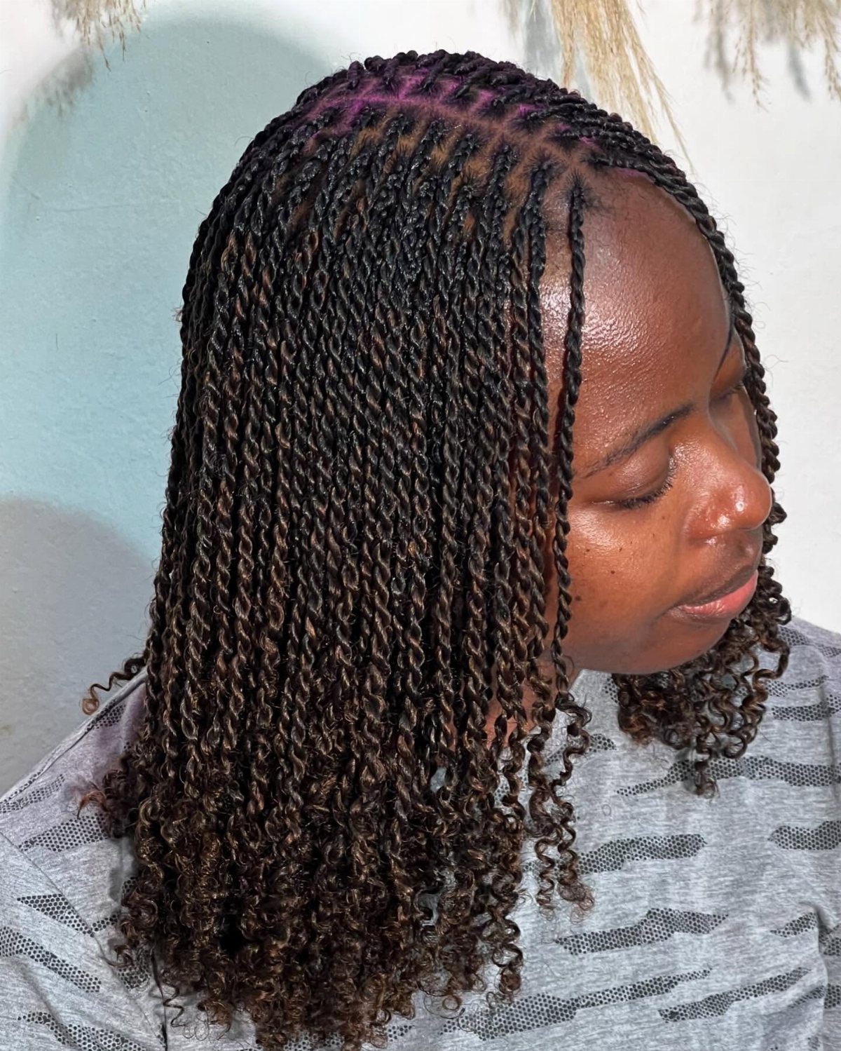 Woman with micro two strand twists and a purple highlight at the crown.