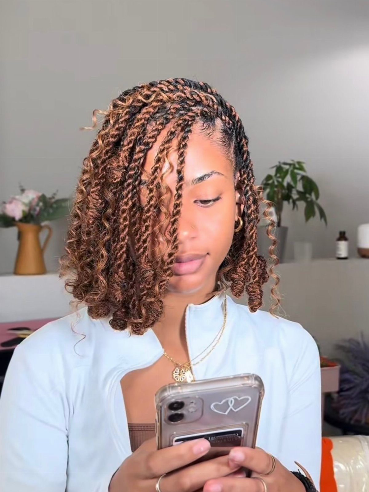 Woman with brown and blonde two strand twist bob hairstyle using a smartphone.