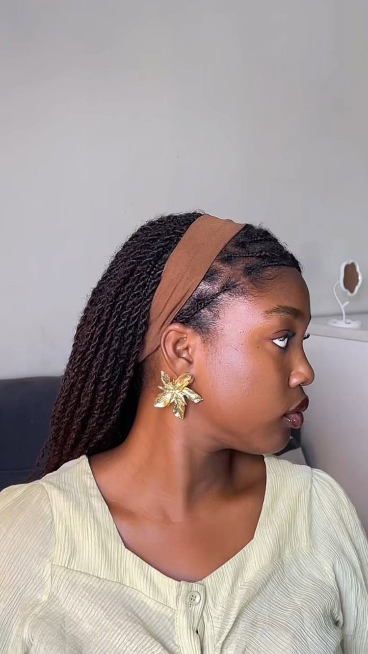 Woman with long two strand twists wearing a brown headband and gold earrings.