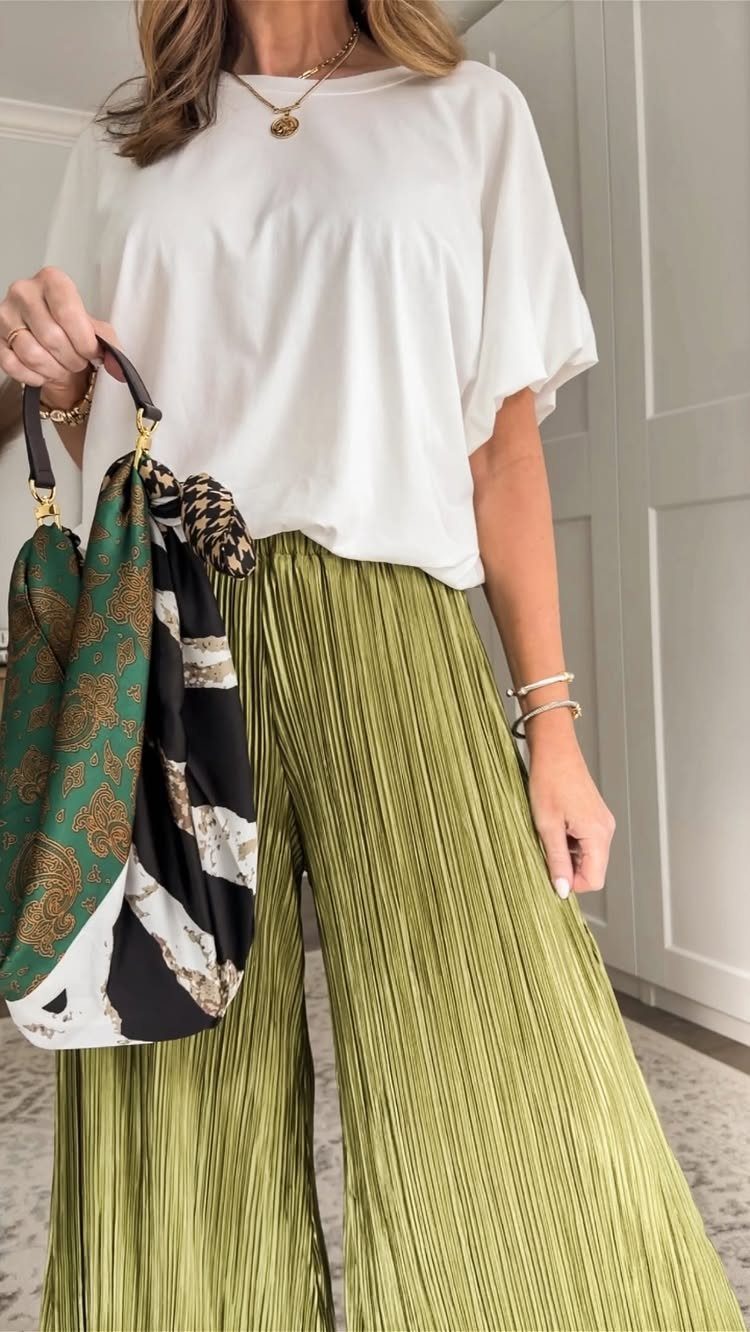 Woman wearing a white blouse and wide-leg pleated olive green flowy pants.