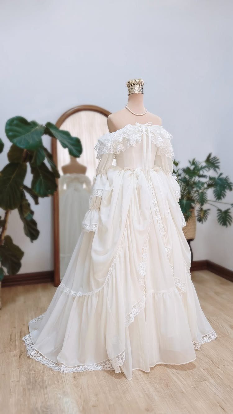 Cream Victorian-style gown with lace and ruffles displayed on a mannequin.