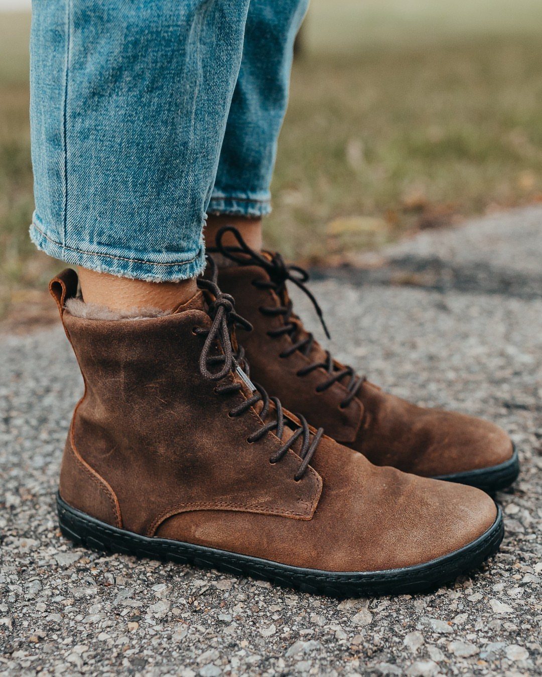 Winter Boots 2026: 8 Styles, From Slouchy to Shearling 6 Brown suede lace-up ankle boots worn with blue denim jeans on asphalt.